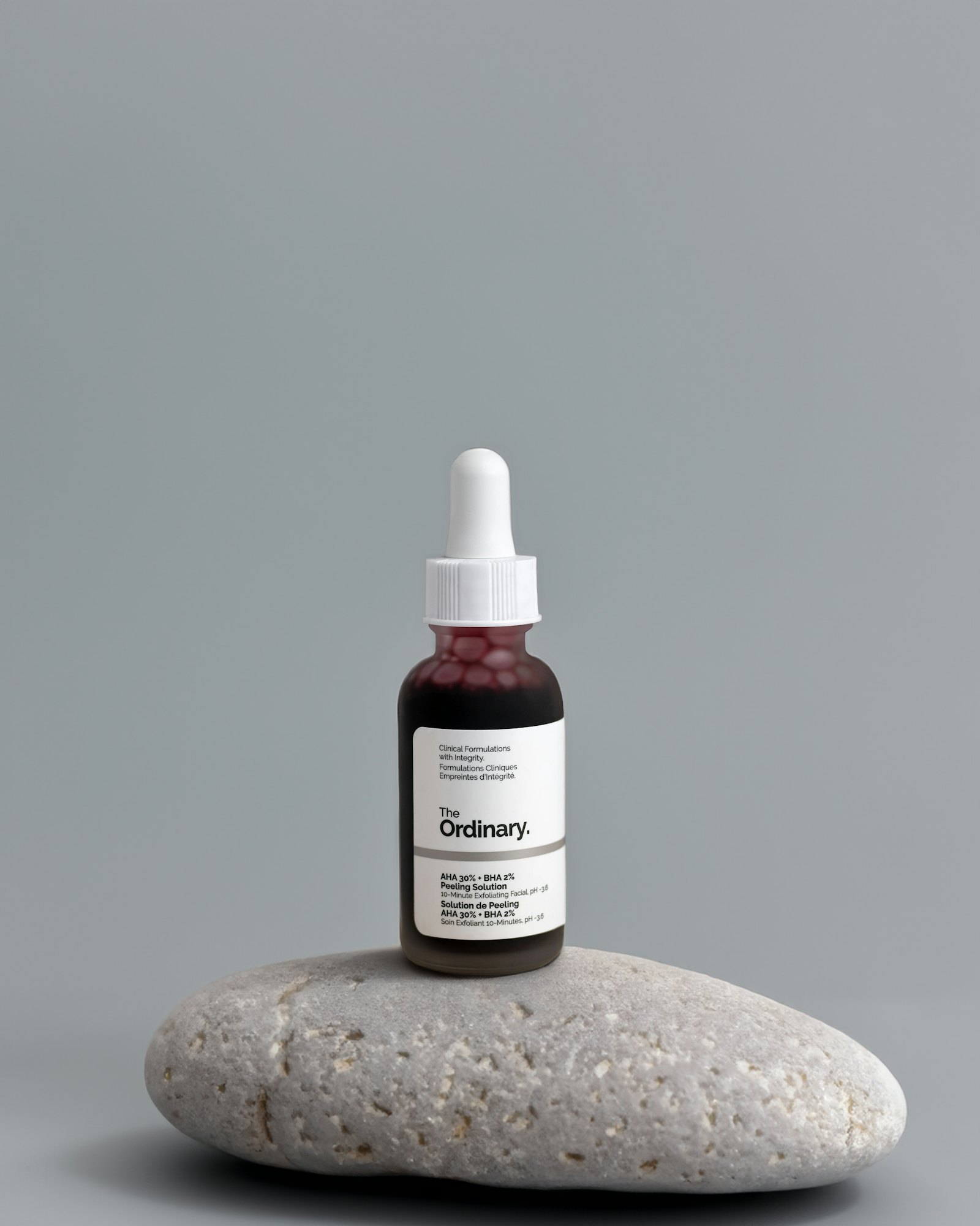 A Saanjh face oil bottle resting on stone, photographed outdoors at dusk